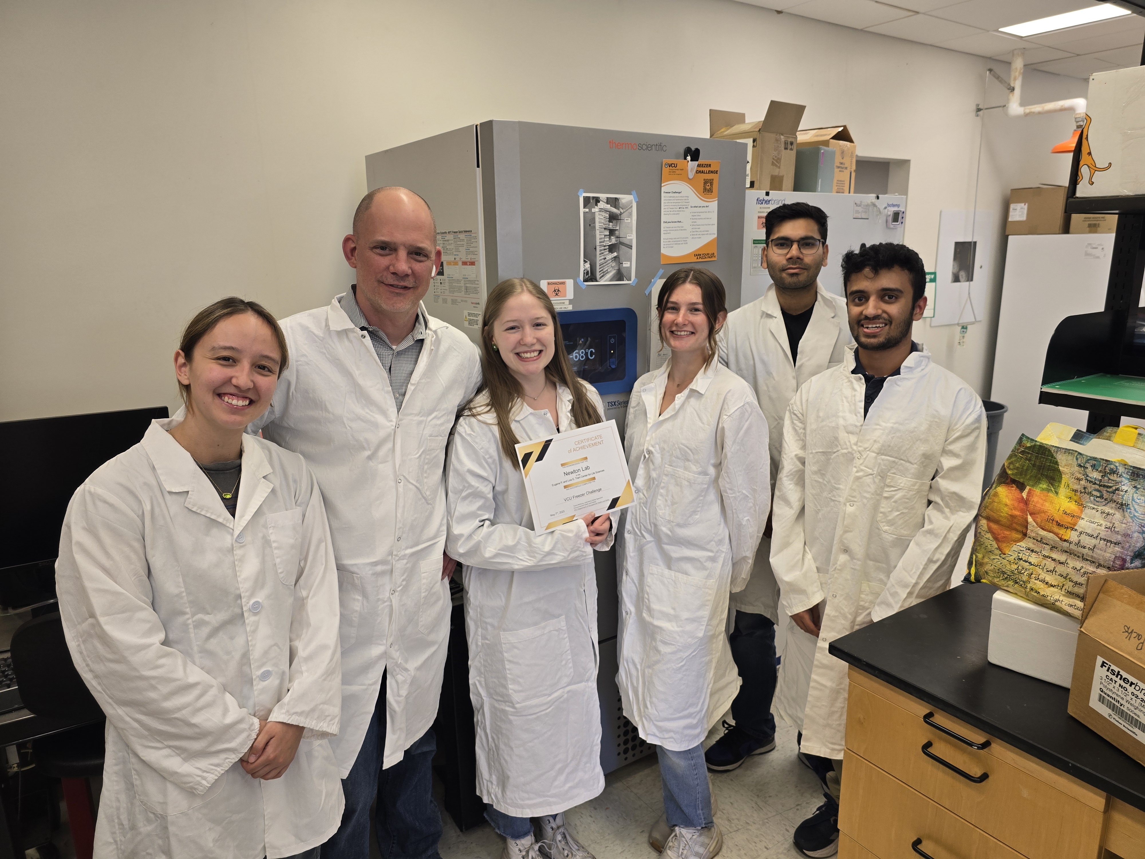 Individuals in lab coats standing in a lab smiling